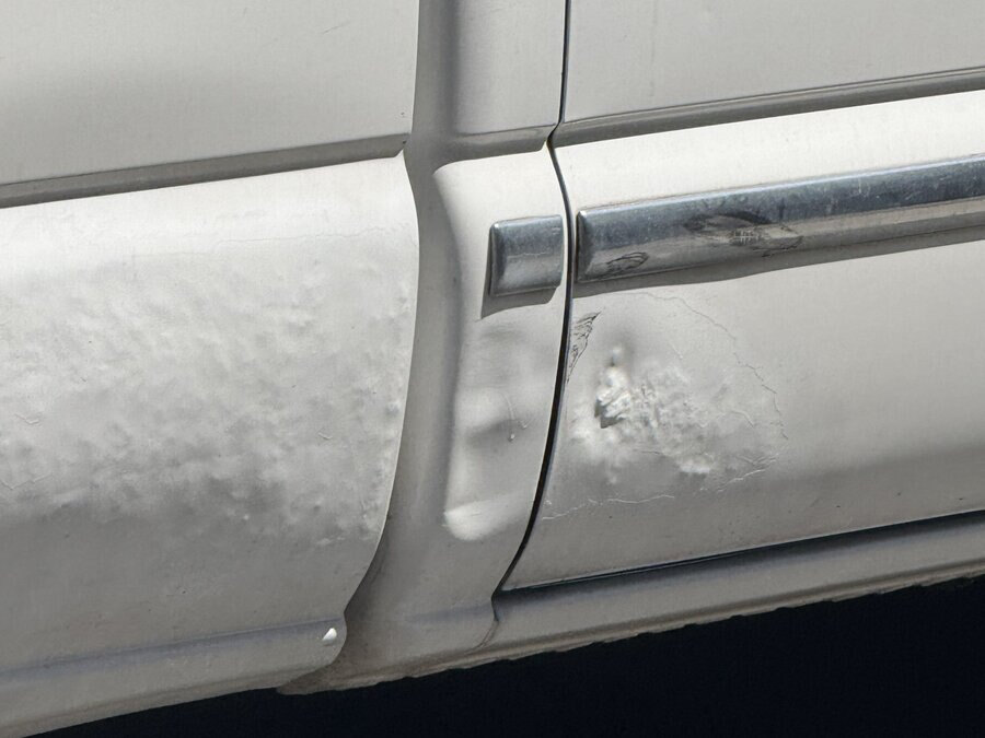 Body filler bubbling and splitting along a door edge months after a repair sold as paintless