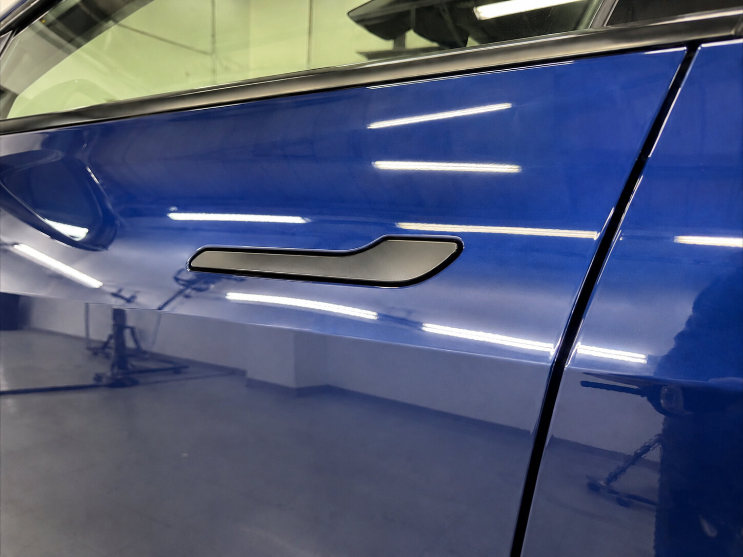 The same blue Tesla aluminum door after paintless dent repair, finish flawless