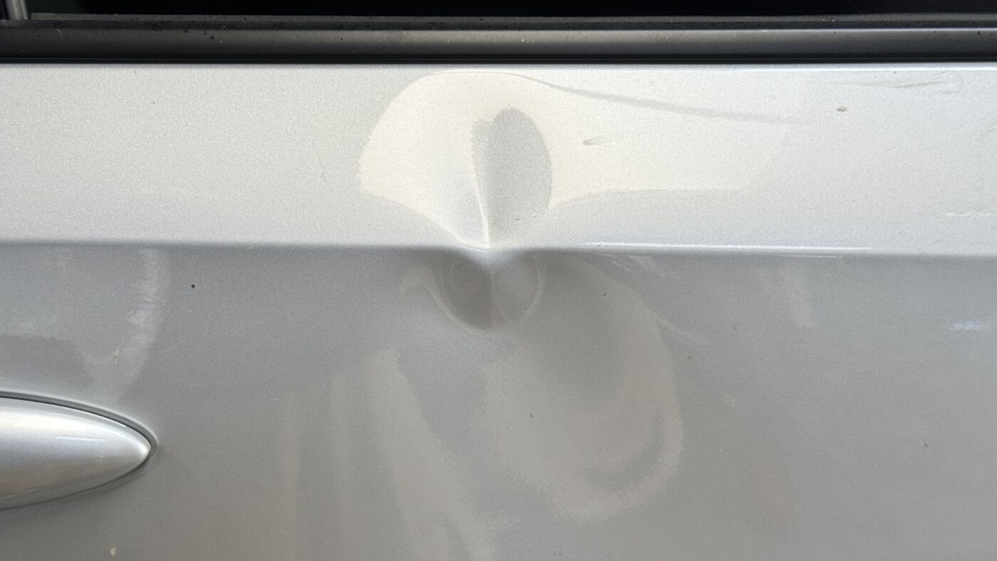 The same door panel before any repair, showing the full dent and crease