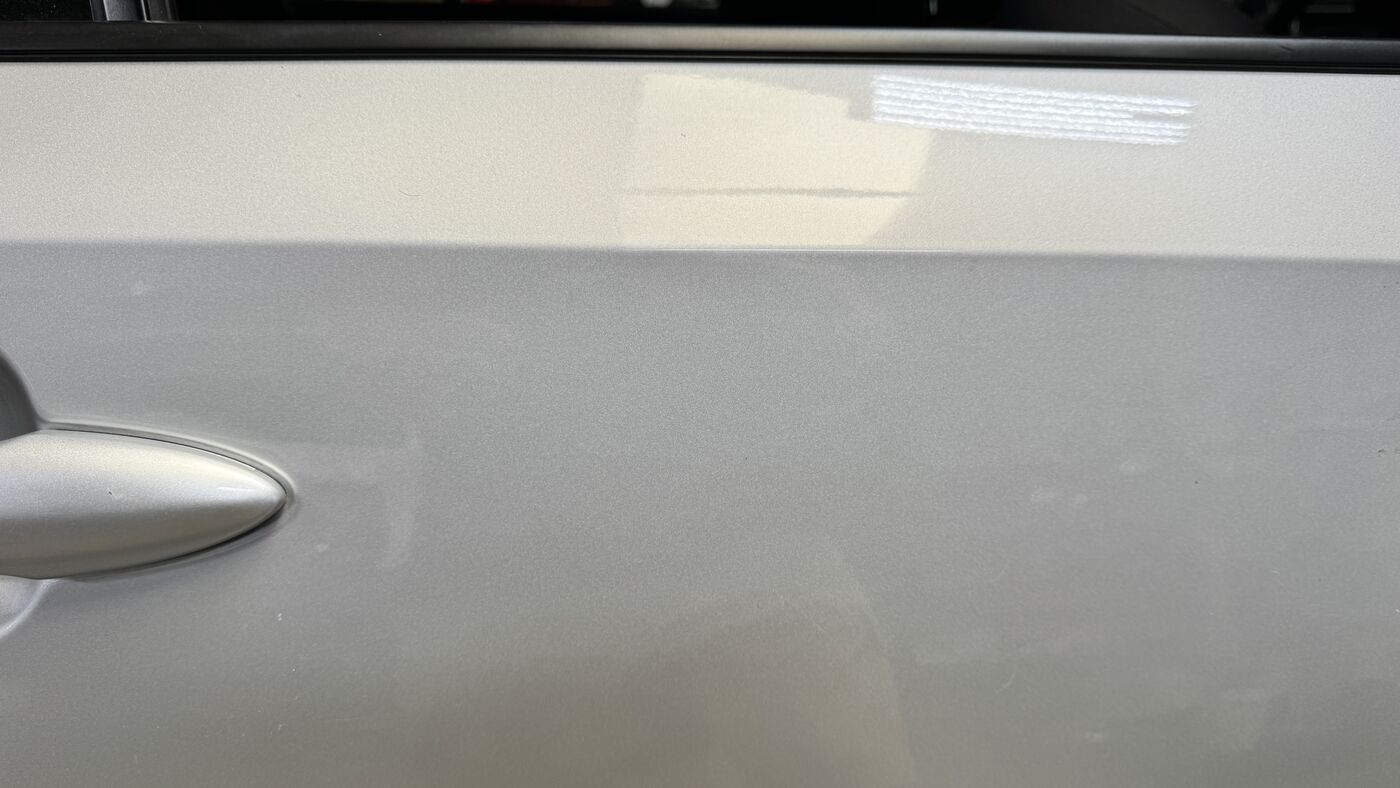 Silver door panel after a Premium standard paintless dent repair, read under raking light
